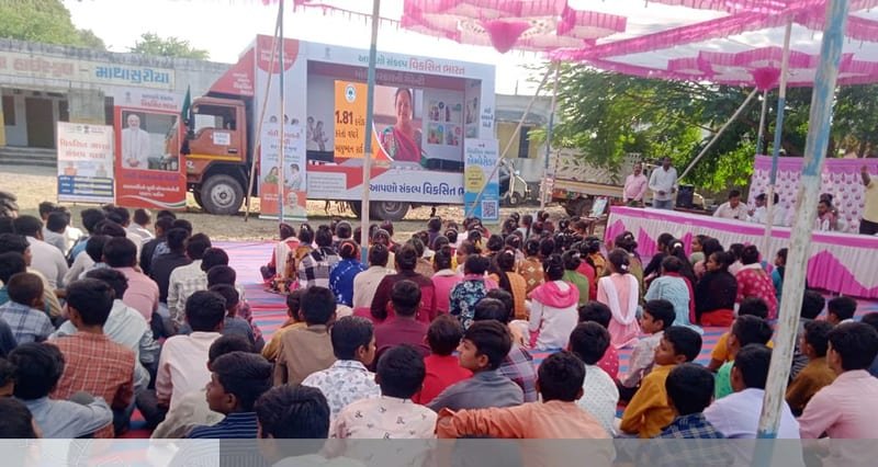 Villagers gathered in front of a branded IEC van screening