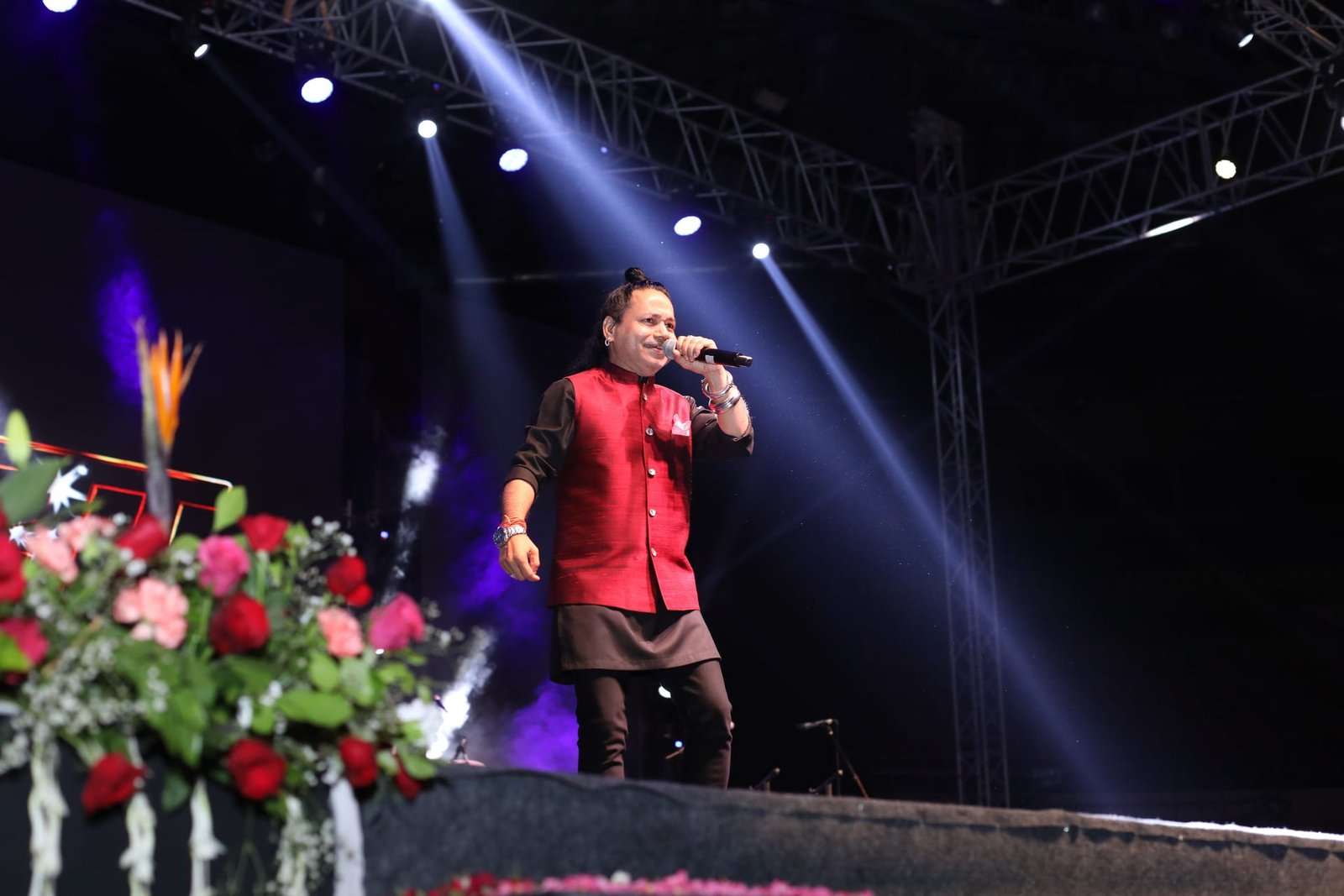 A singer performing under stage lighting at a Smriti Films event